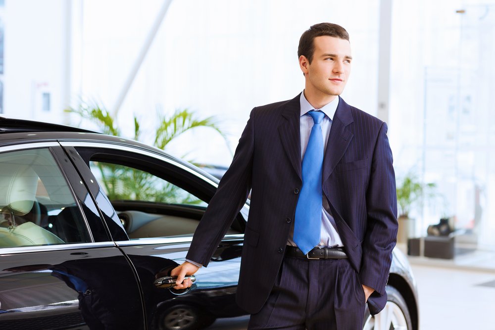 man in suit next to car